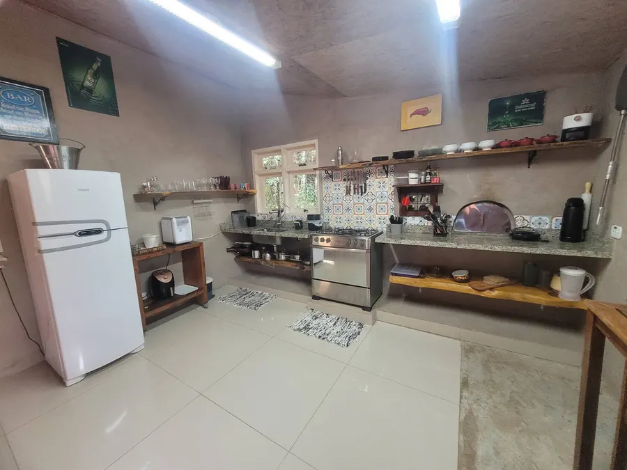 Cozinha gourmet completa com fogão, forno de pizza, prateleiras de madeira e azulejos decorados