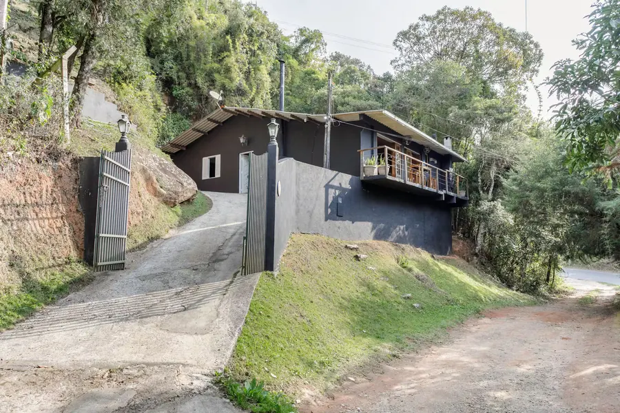 Chegada à Guttos House: portão, rampa de acesso e a casa com varanda entre as árvores