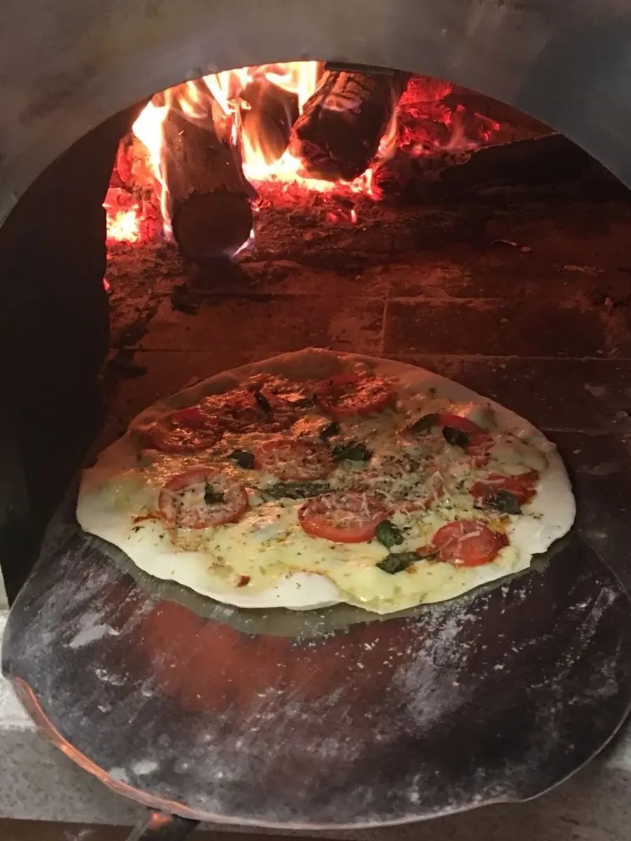 Pizza assando no forno a lenha da Guttos House