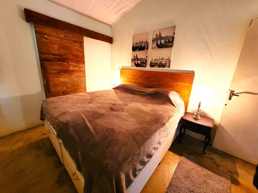 Quarto com cama ampla, cabeceira de madeira e luz quente
